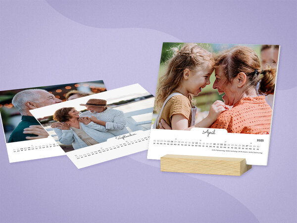 Quadratische Kalenderblätter stehen frei in einem Holzstandfuß. Kalender hat weißes Design, mit Fotos von Großeltern..